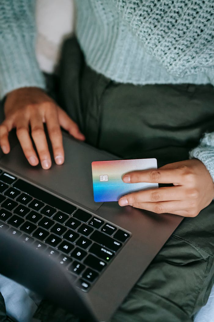 Crop ethnic buyer with plastic card shopping online on laptop